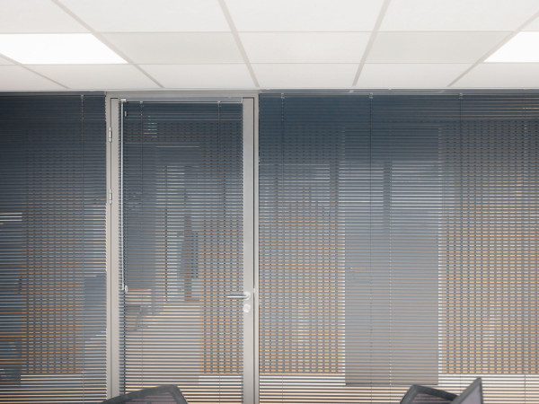 Donkergrijze horizontale jaloezieën voor privacy in de vergaderruimte van Beko Groothandel.